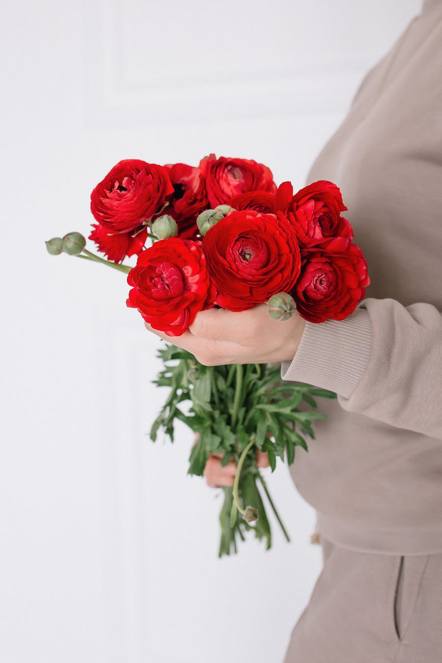 a person holding bouquet of persian buttercup