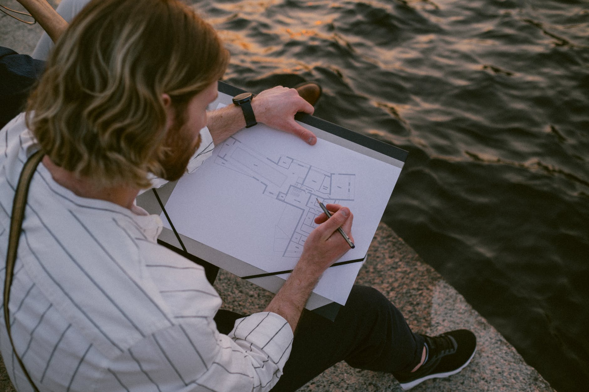 man in white stripes long sleeves drawing in front of a water