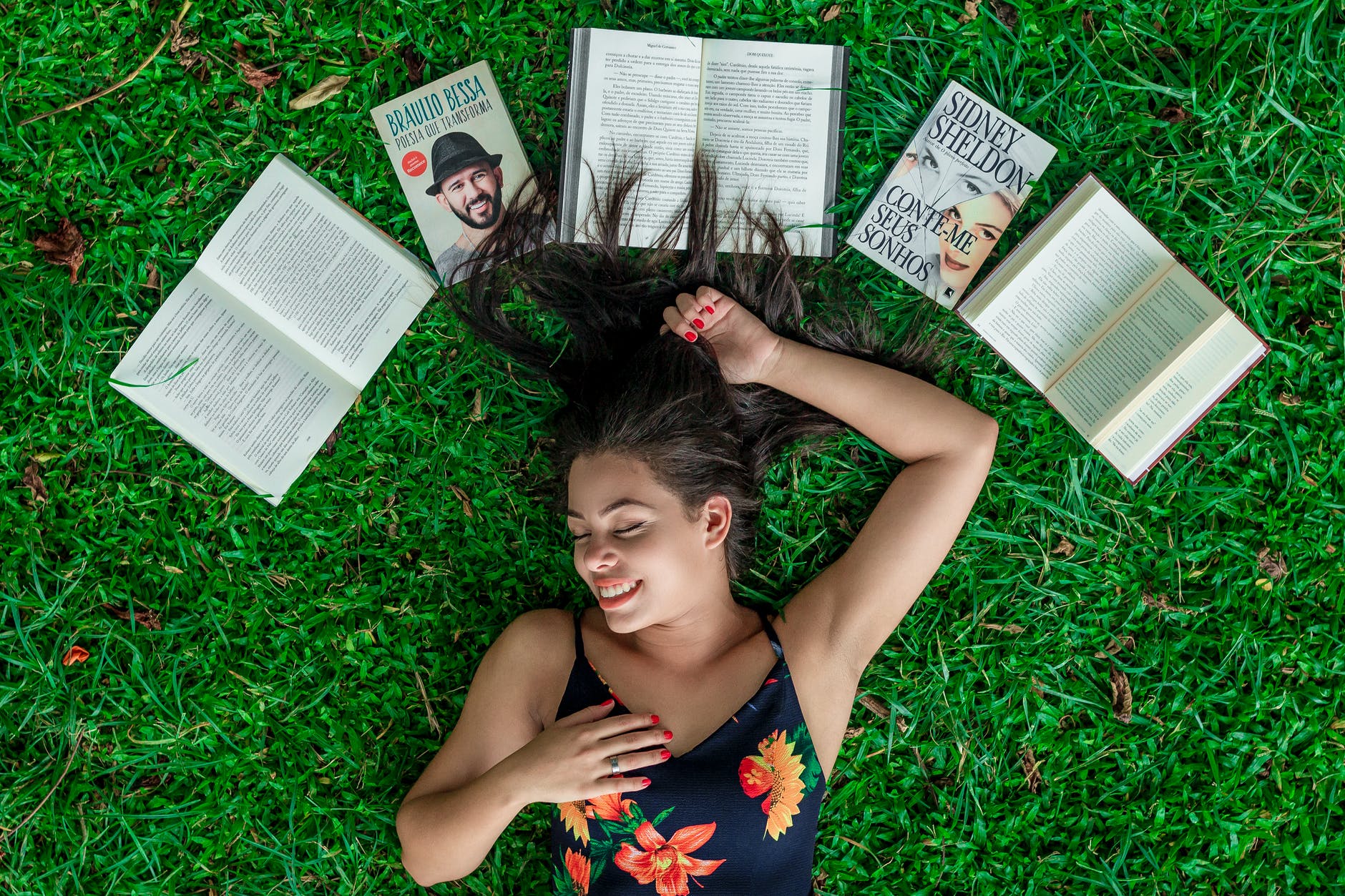 woman lying down on grass beside opened books