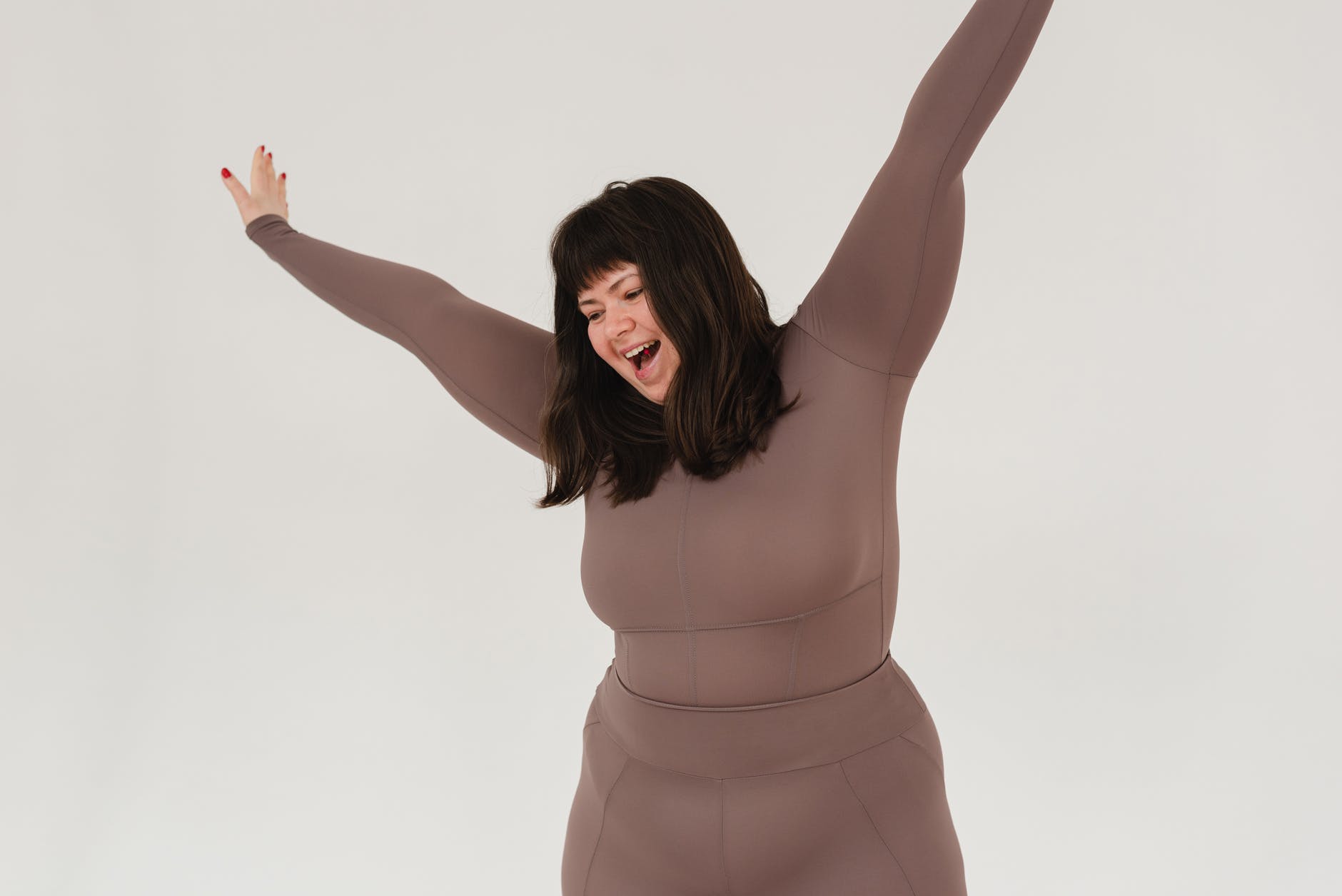 excited young overweight woman screaming while standing in studio with raised arms