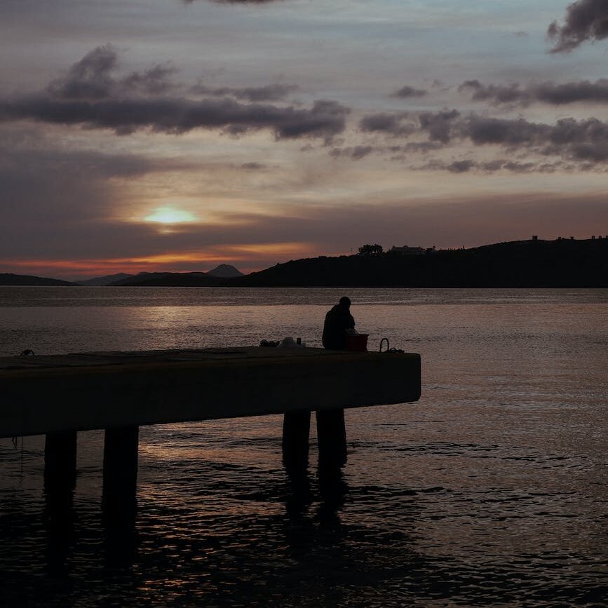 silhouette of a person sitting on a dock
